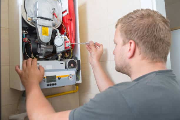 Plombier chauffagiste qui réalise la maintenance annuelle d'une chaudière gaz à condensation