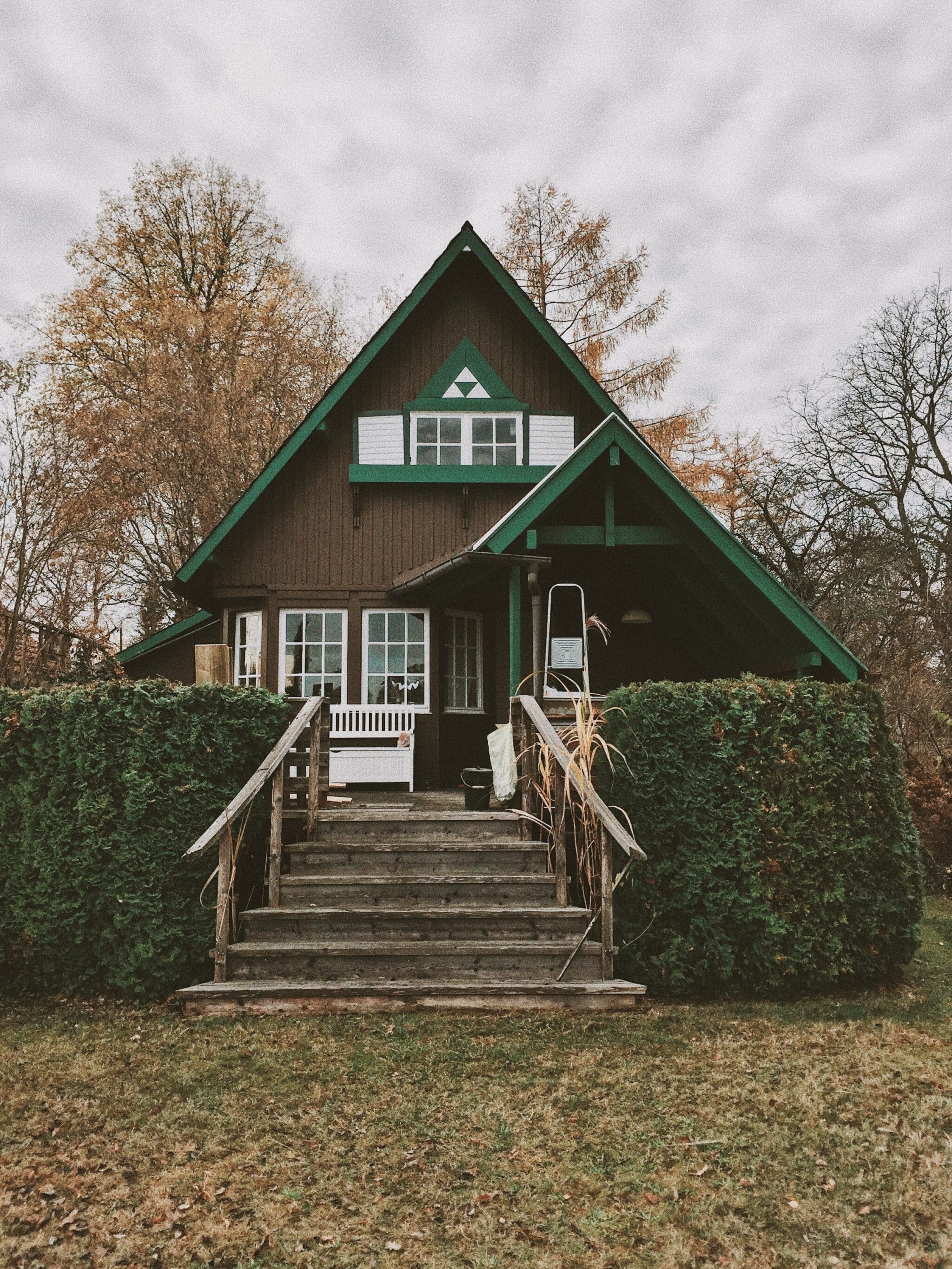 Maison bois et peinte en vert avec arbres autour